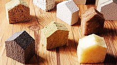 Nahaufnahme verschiedener geschliffener Isolierblöcke in Häuserform auf einem Holztisch.