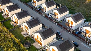 Luftaufnahme einer Wohnsiedlung mit mehreren modernen Einfamilienhäusern mit Solarpaneelen auf den Dächern