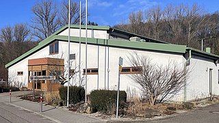 Blick auf ein weißes Gebäude mit grünem Dach, die Hagwaldhalle in Pfinztal