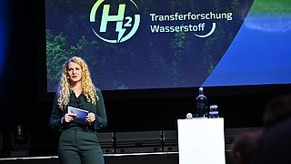 Zu sehen ist die Moderatorin des Events auf der Bühne.