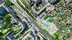 Luftaufnahme einer Stadt mit hohen Wohngebäuden, breiten Straßen und grünen Flächen.