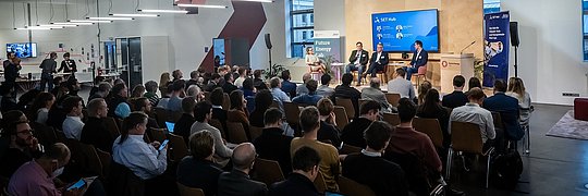 Vier Menschen sitzen auf der Bühne in einer Diskussions-runde im Future Energy Lab. Im Hintergrund ist der Titel des Events auf einem Bild-schirm zu sehen.