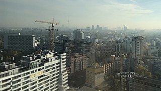 Stadtpanorama mit Hochhäusern, Baukränen und leicht bewölktem Himmel bei Tageslicht