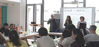 Eine Gruppe Menschen sitzt im Rahmen eines Workshops um einen runden Tisch zusammen.