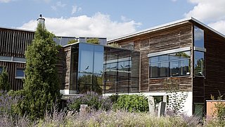 Ein holzvertäfeltes Bürogebaude mit Solarthermieanlagen auf dem Dach.