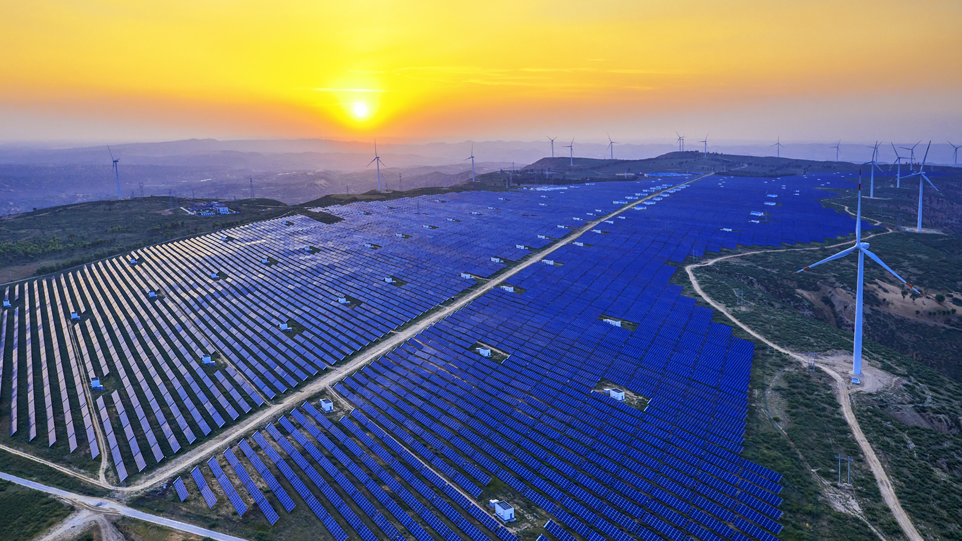 Landschaft mit Solarpanelen und Windrädern im Sonnenschein